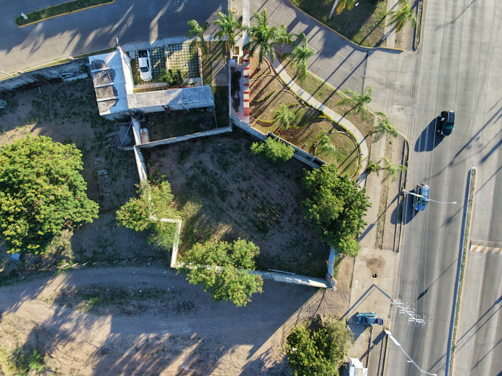 Vue aérienne du terrain clôturé, entre palmiers et rue